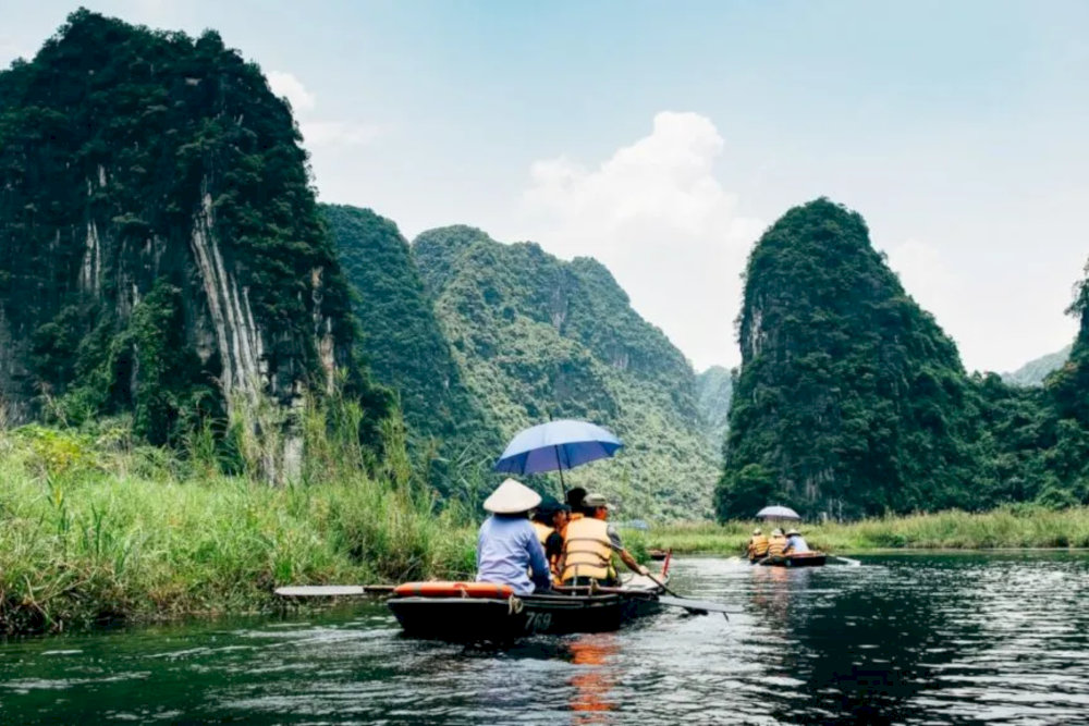 Visitors are gently rowed through vast rice paddies and beneath towering limestone caves